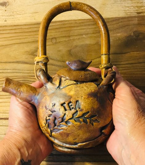 botanical teapot in hands'